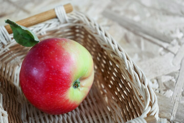 Red apple in a wicker basket on a wooden background, copy space