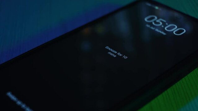 Waking up in the morning. The alarm clock on the phone rings at 5:00 o'clock in the morning. Early start of the day. The hand swipes across the screen. Getting up to work or study