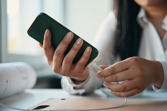 Female engineer charging her smartphone in workplace