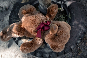 A toy teddy bear lies on an old tire