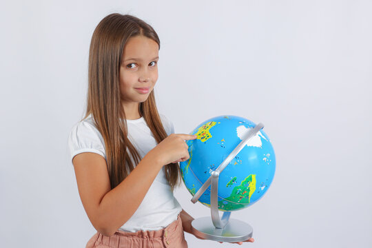 the girl looks at the camera and points her finger at the globe. High quality photo