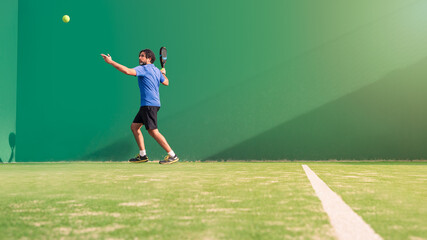 Monitor practicing paddle sport on the outdoor court. Man teaching padel class