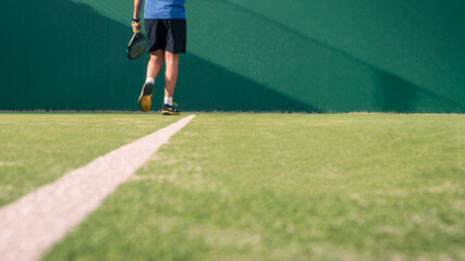 Monitor practicing paddle sport on the outdoor court. Man teaching padel class