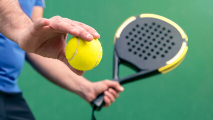 Professional monitor of padel holding black racket on green court. Game concept