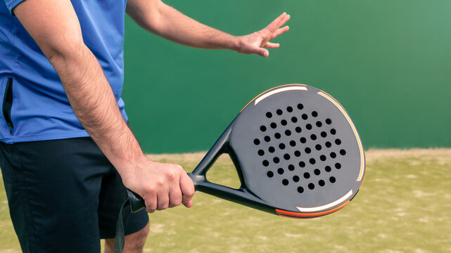 Monitor practicing paddle sport with a black padel racket on a green court grass - Powered by Adobe