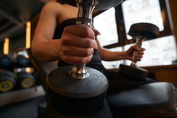 Female athlete performing seated dumbbell exercise at gym