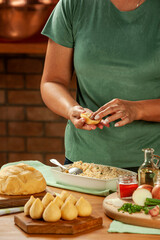 Woman hands preparing brazilian croquette (coxinha de frango) on a wooden table.