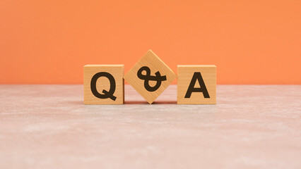 Q and A - acronym from wooden blocks with letters, questions and answers concept. orange...