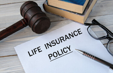 LIFE INSURANCE POLICY - words on white paper with the background of the judge's hammer, glasses and...