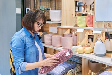 Mature woman choosing sofa cushions in a home decor store