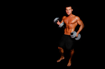 Young attractive sportsman with dumbbells. Male athletic body.