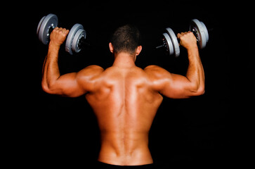 Fototapeta na wymiar Young attractive sportsman with dumbbells. Male athletic body.
