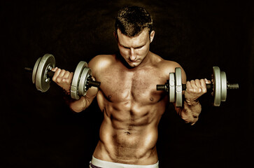 Fototapeta na wymiar Young attractive sportsman with dumbbells. Male athletic body.