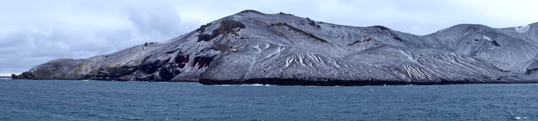 Panorama of snow dusted mountains around the pass at the entrance to the crater bay in Deception Island, Antarctica