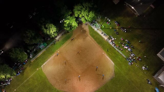 Aerial rural community softball game night overhead. Small rural community play softball. Village city celebration. Team spirit and teamwork. Sports, recreation and healthy exercise.