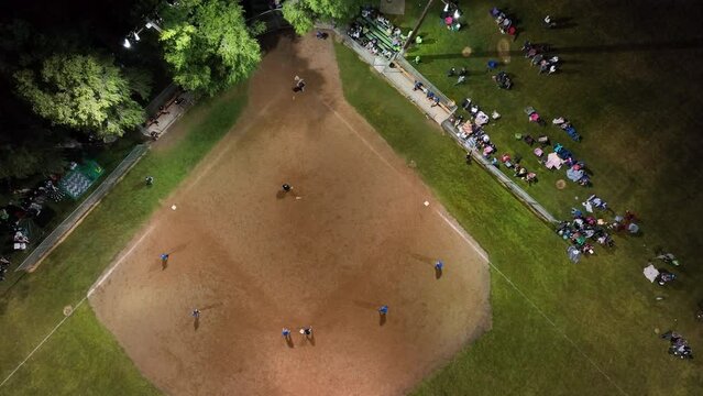 Aerial softball game night lights city park. Small rural community play softball. Village city celebration. Team spirit and teamwork. Sports, recreation and healthy exercise.