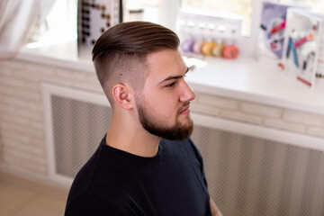 Brunette man with stylish haircut on barbershop background