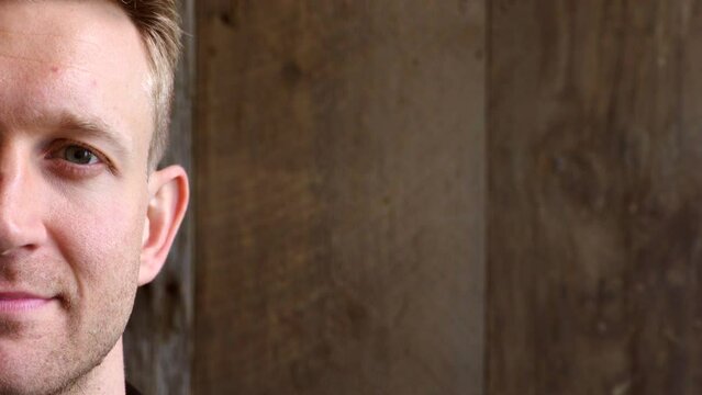 Portrait of a man staring and blinking against a wooden background with copy space. Closeup of face of a handsome young guy with a carefree and content expression looking focused and determined