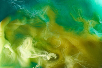 Liquid fluid art abstract background. Green, yellow dancing acrylic paints underwater, space smoke ocean, color explosion