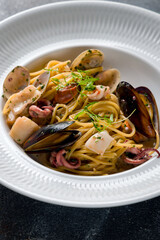 Pasta spaghetti with seafood on white plate, vertical, macro close up