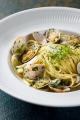 Linguini with vongole in wine sauce on white plate, vertical, macro close up