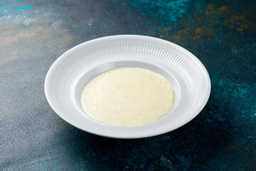 millet porridge on a white plate on blue concrete table