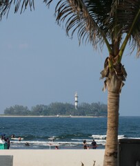 paisaje de playa con palma, arena, personas , mar e isla con arboles y un faro