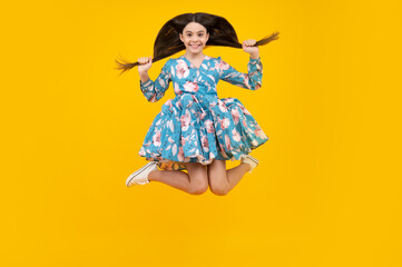 Full length overjoyed teenager kid girl 12 13 14 year jumping old isolated on yellow background studio. Funny jump. Child in summer movement dress.