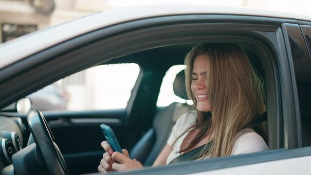 Young woman using smartphone sitting on car at street