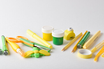 Various yellow and green stationery are scattered on a white background.