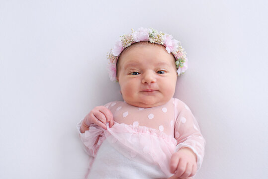 Beautiful little infant baby girl, has happy sleep face, dressed in suit and headband with flowers. Child close up portrait. Lifestyle instagram newborn concept. Amazing kids.