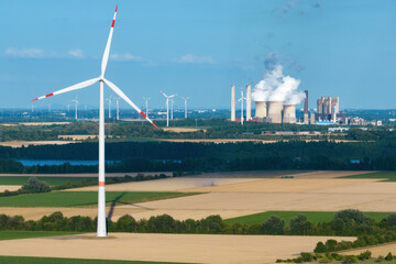 Aerial view of a wind farm with a coal-fired power plant in the background