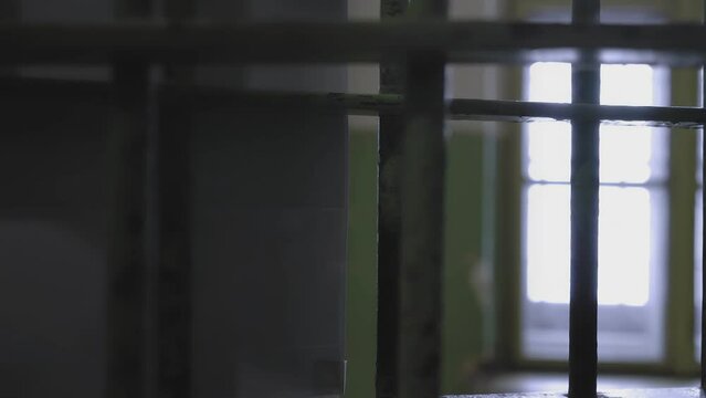 Panoramic camera from a dark prison cell through the bars close-up of a man passing by