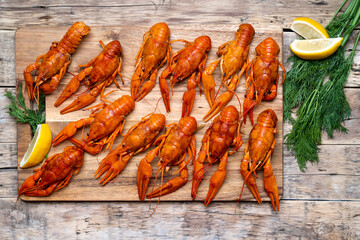 boiled crayfish on a wooden aged table and a wooden board with dill and lemon