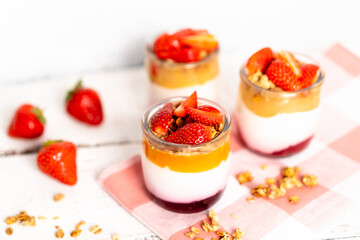Fruit yogurt berry with muesli and fresh strawberries, on a white wooden background