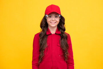 Worker teenager child wearing overalls red, cap and protect glasses. Studio shot portrait isolated on yellow background. Happy face, positive and smiling emotions of teenager girl.