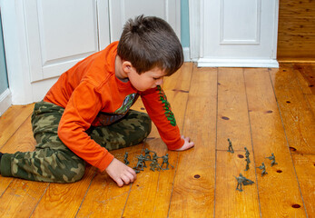 young Boy with toy soldiers on the floor has a pretend war