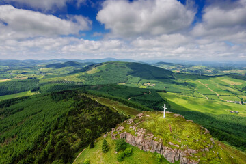Tall white Catholic cross on top of Devils bit mountain in county Tipperary, Ireland. Aerial view. Beautiful landscape with green fields and forests in the background. Irish landscape.