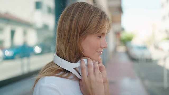 Young blonde girl smiling confident listening to music and dancing at street