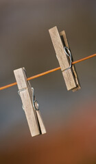 Closeup of two clothing pegs on a washing line outside against a blurred background. Wooden...