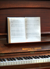 Closeup of a vintage piano and keyboard with a sheet music book. An empty antique or wooden musical instrument for playing classical jazz or used for old traditional songwriting and rehearsals