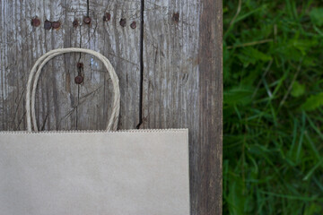 eco paper shopping bag on the rustic wooden table near green grasses