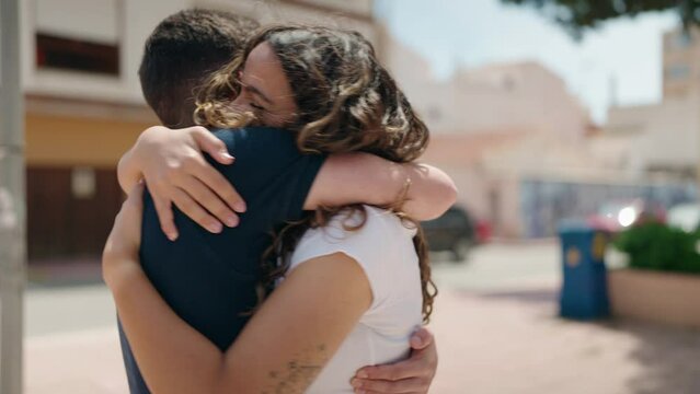 Young hispanic couple smiling confident hugging each other at street