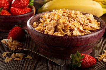 Corn flakes in the bowl with berries on the table.