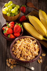 Corn flakes in the bowl with berries on the table.
