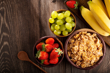 Corn flakes in the bowl with berries on the table.