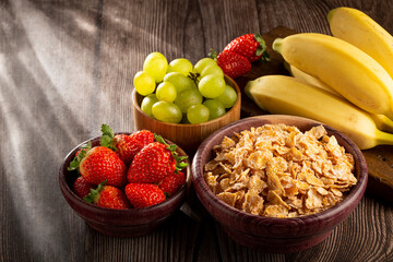 Corn flakes in the bowl with berries on the table.