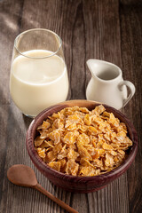Corn flakes in bowl and glass of milk on table.