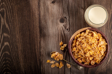 Corn flakes in bowl and glass of milk on table.