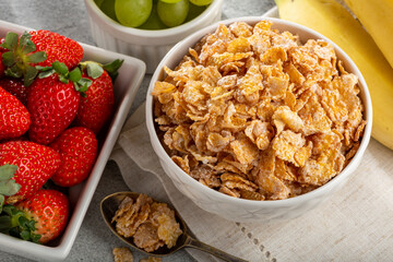 Corn flakes in the bowl with berries on the table.